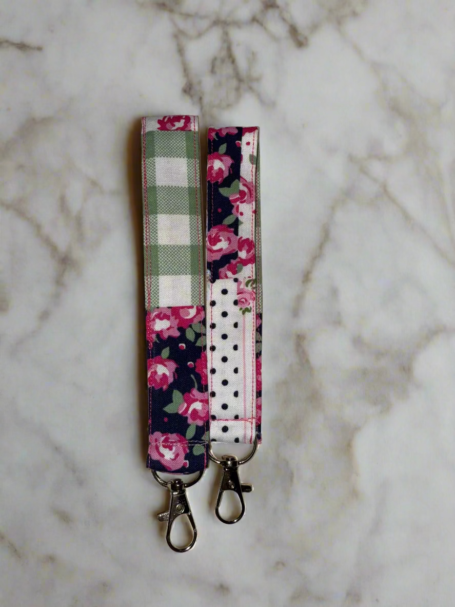 Two fabric keychains with floral and polka dot patterns on a beige surface.