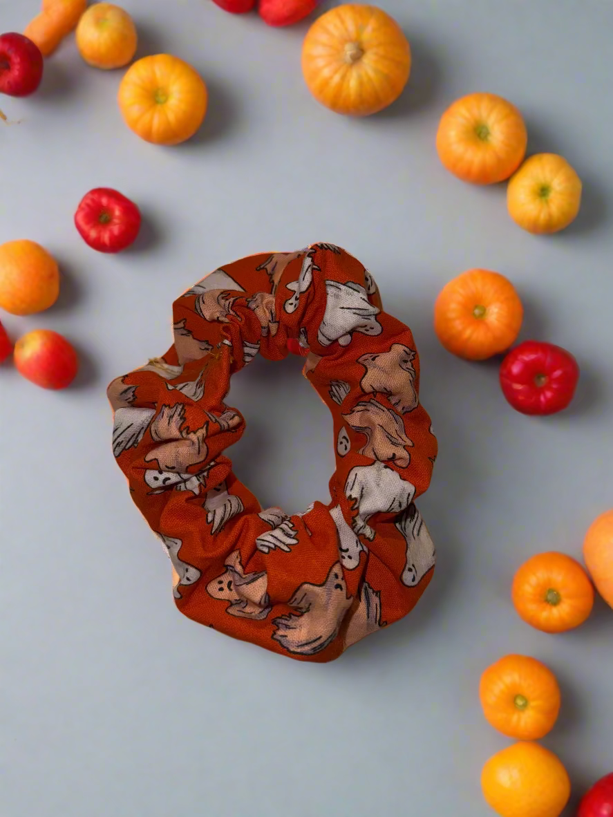 Orange scrunchie with ghosts pattern on a white fabric background