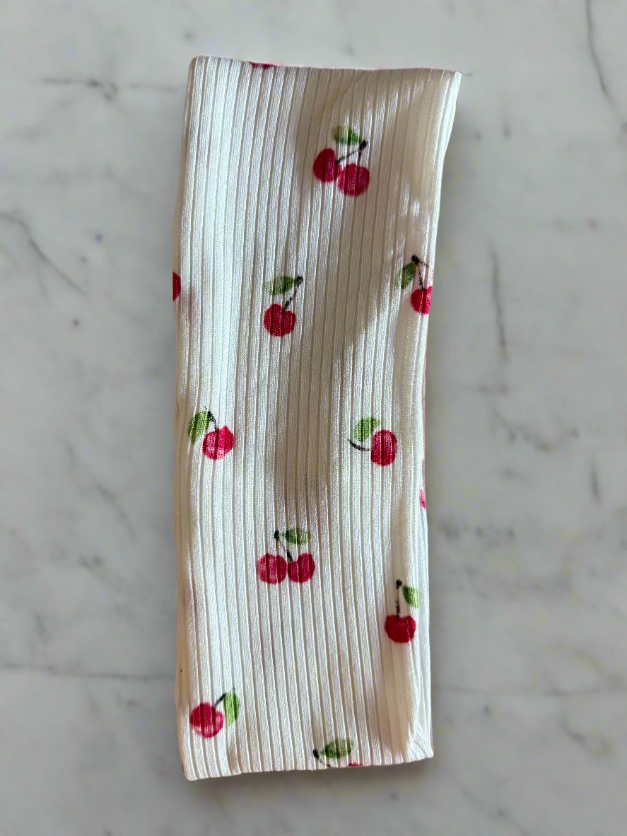 White fabric with red cherry pattern on a floral background